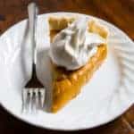 Egg-free, dairy-free, gluten-free pumpkin pie on plate with whipped cream.
