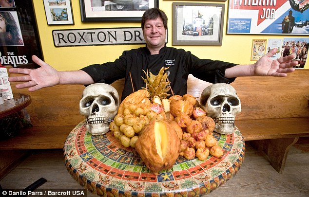 Festive: Chris Sell, owner of the chip shop, proudly sits with his freshly fried fruit platter - designed for Halloween
