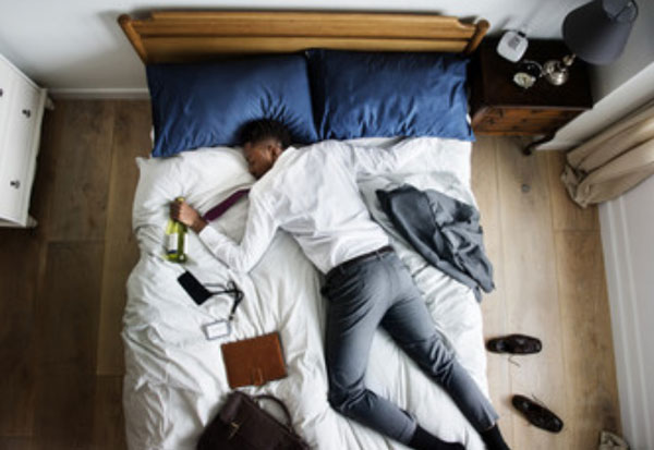 Уставший мужчина лежит на кровати в уличной одежде