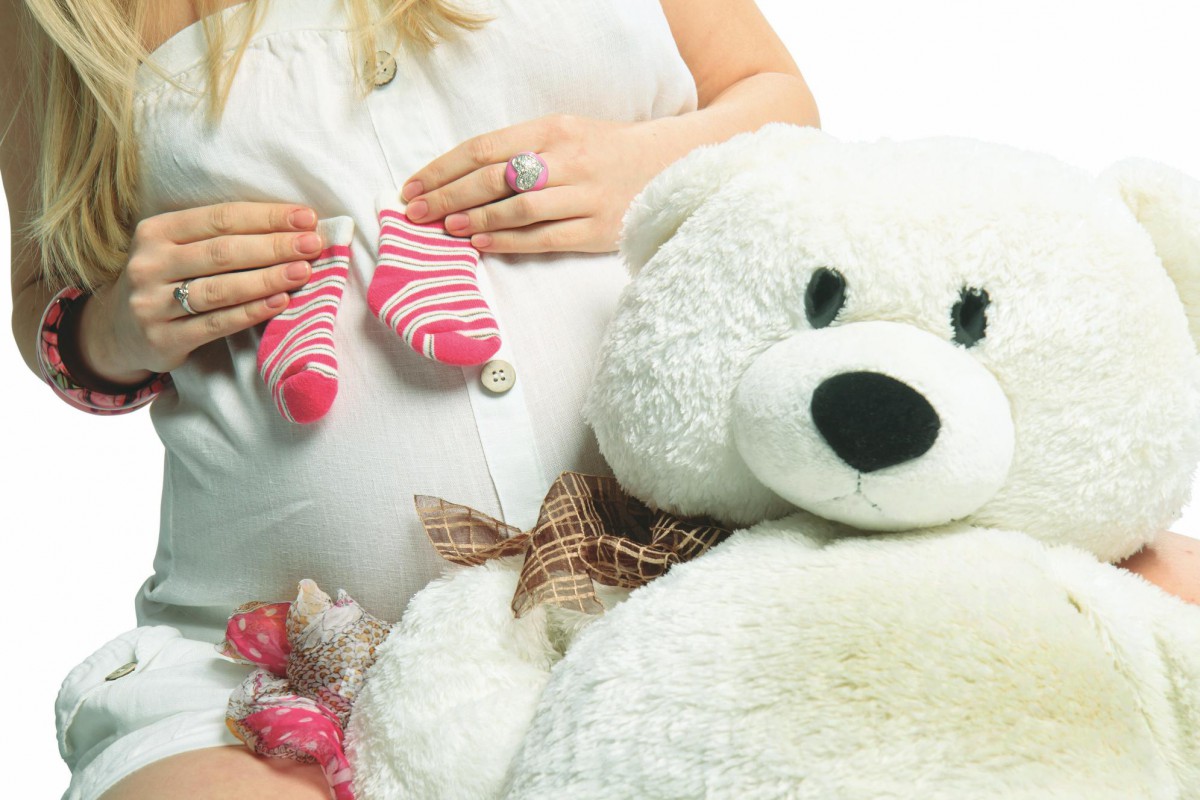 Беременная женщина держит в руках носочки