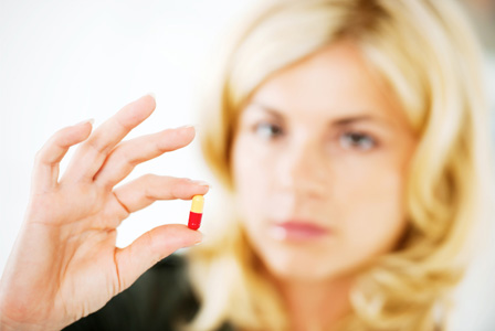 Женщина держит таблетку